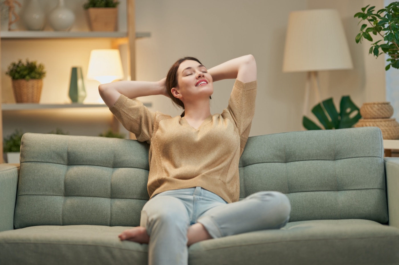 Woman relaxing on a sage-green couch in a clean living room