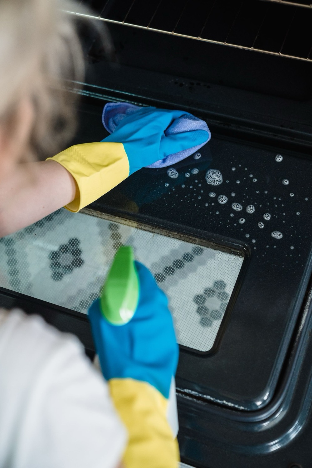Detail-cleaning the inside of an oven door during a deep clean