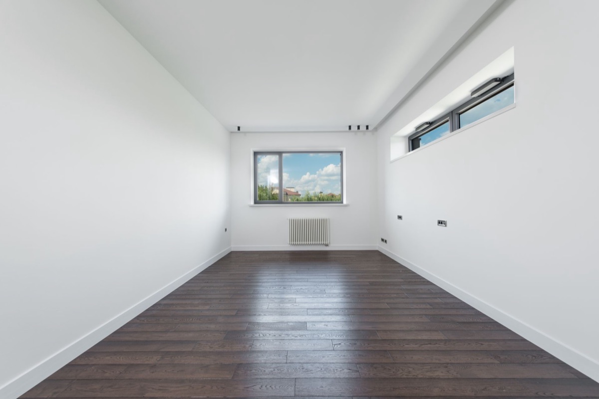 Empty, freshly cleaned apartment room with hardwood floors, ready for move-in