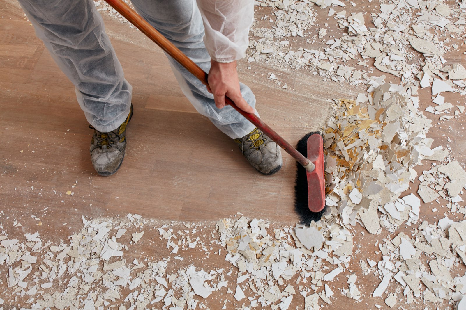 Cleaner sweeping up drywall dust and construction debris during a post-renovation clean