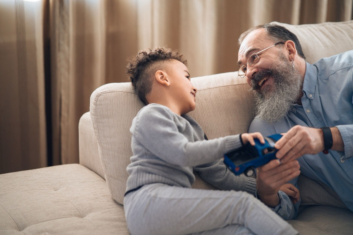 Grandfather and grandson playing together on a clean sofa